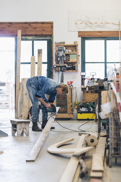 Woman Artist Cutting Wood With Power Saw In A Workshop