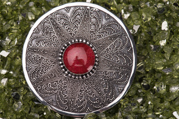 Silver fibula against a green sparkling background