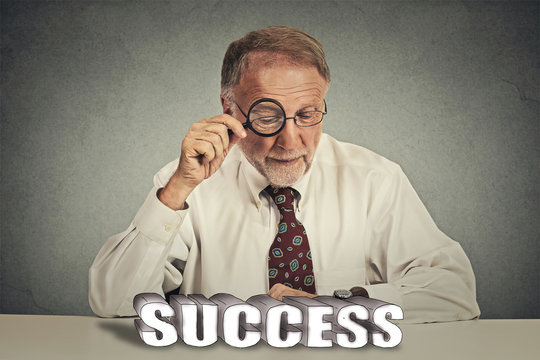 business man looking through magnifying glass at success sign