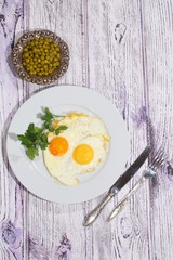 Fried eggs with fresh parsley and a green peas