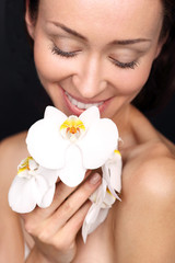 Obraz na płótnie Canvas Portret pięknej młodej szczęśliwej kobiety z kwiatami białego storczyka