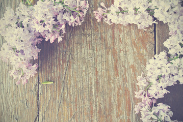 Rustic wooden table with lilac flowers on it; can be used as a background. Image filtered in faded, washed out, retro style; romantic vintage concept.