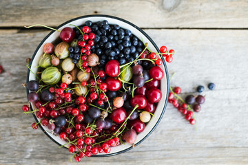 Different fresh berries in a pot on the wooden background © olllinka2