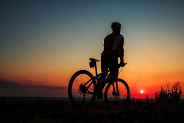 Obraz premium Sylwetka rowerzysty i rowerów na tle nieba.