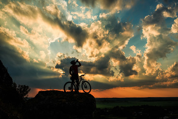 Obraz premium Silhouette of a biker and bicycle on sky background.