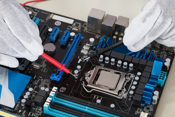 Person Hands Checking Motherboard With Multimeter