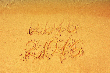 2015 - 2016 on sea sand. 2015 almost washed away a wave. Happy New Year 2016 replace 2015 concept on sea beach . Leaving and coming year