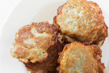 hash browns/ potatoes fritters with a golden crust in a white ceramic plate closeup