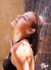 Woman under refreshing cold shower
