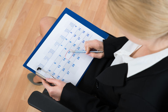 Businesswoman Marking Date On Calendar