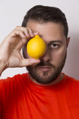 Vegetarian man holding a lemon in front of the eye