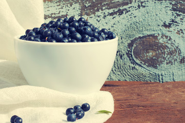 Fresh  blueberries in a white ceramic bowl on a wooden surface