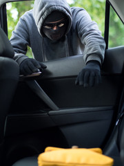 Transportation crime concept .Thief stealing bag from the car