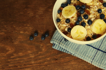 Oat flakes with fresh blueberries and banana in a white bowl on a wooden surface