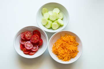 Dishes of red romatoes, green cucumbers and orange carrots