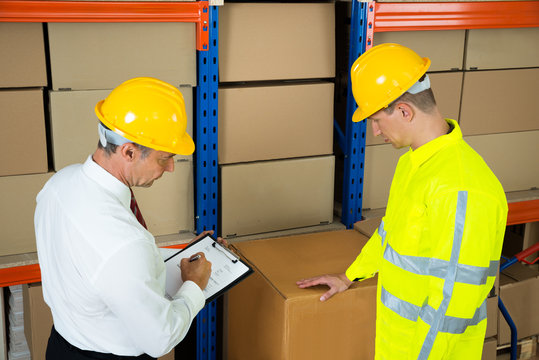 Warehouse Worker Checking The Inventory With Manager