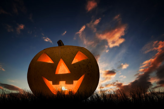 Halloween pumpkin glowing under dark sunset, night sky. Jack o'lantern