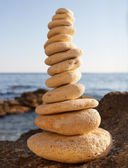 Fototapeta na wymiar Balancing of white pebbles each other on the seacoast with empty