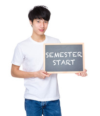 Young man with chalkboard showing phrases of semester start © leungchopan