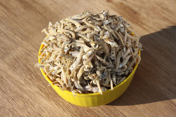 dried fish in yellow bowl isolated on wood background