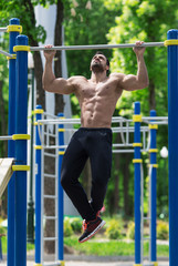 Fototapeta na wymiar athlete doing pull-up on horizontal bar.Mans fitness outdoor.