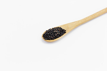 Black Sesame Seeds in wooden spoon isolated on white background
