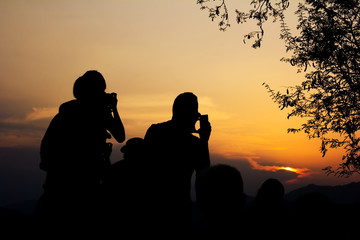 Silhouette of travelers with camera during sunset