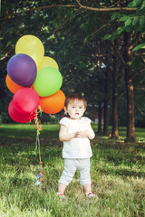 Portrait of cute adorable little asian girl child one years old, in white pants shirt, standing with balloons on field meadow on sunset, concept of happy birthday holiday, toned with Instagram filters