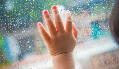 Rain drops on the car window and children hand . Abstract backgr
