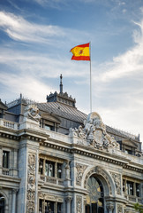 Fototapeta na wymiar The flag of Spain fluttering on building of the Bank of Spain