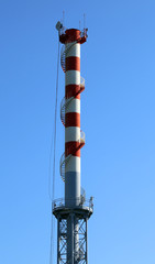 highest red and white smokestack with  the antennas