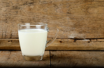 Glass with milk on the wooden background