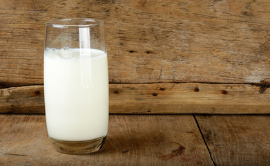 Glass with milk on the wooden background