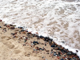 sandy beach with small stones and water wave