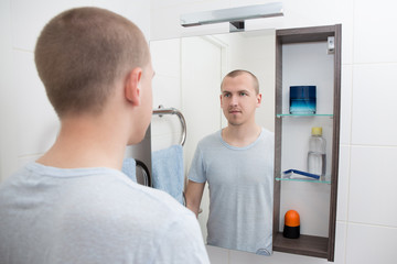 man looking at mirror in bathroom