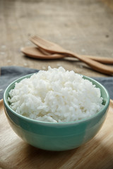 Cooked rice with a spoon and fork on wooden table - soft focus