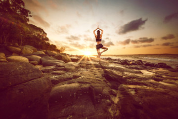 Woman meditates on rocks by the beach