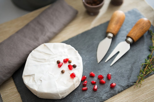 Fresh Camembert cheese on a slate with pomegranate seeds