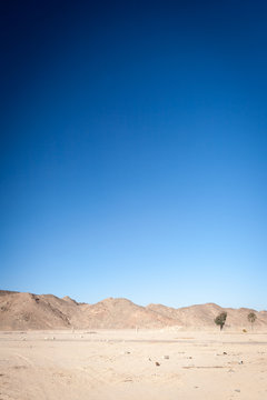 Egyptian desert. Hot and dusty Egyptian landscape bleaching in the hot sun with the Red Sea mountain in the distance.