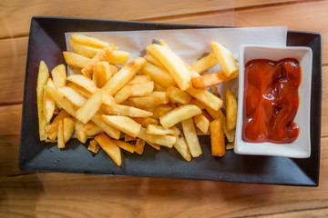 French fries in black plate serv with tomato and chilli souse