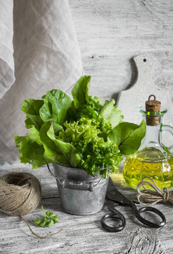 fresh green salad in a metal bucket on a light wooden background, vintage style