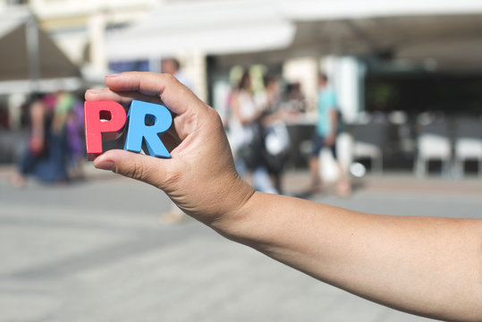 Women hold wooden letters PR