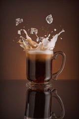 Ice cappuccino splash, refreshing mug of coffee on brown background.