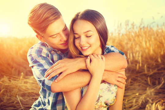 Happy couple kissing and hugging outdoors on wheat field, love concept