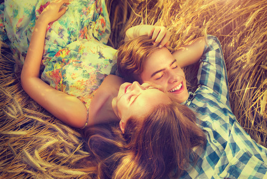 Happy couple relaxing outdoors on wheat field, love concept