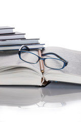 Eyeglasses and pencil on the book. A stack of books.