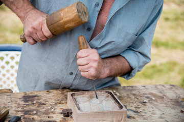 Old woodcarver working with mallet and chiesel, vintage style