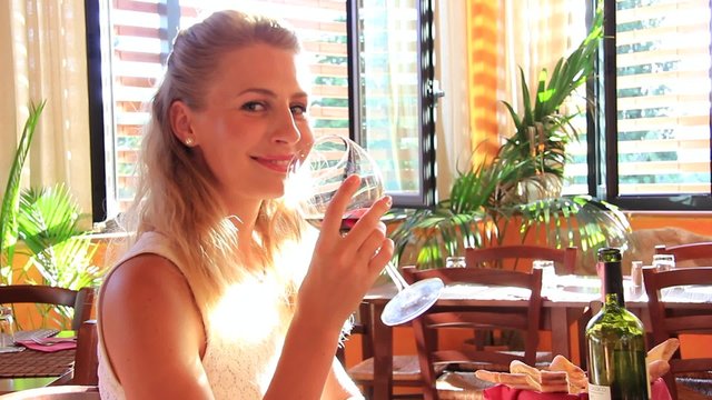Young woman enjoying a glass of red wine in a restaurant