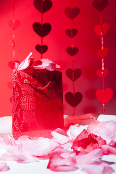 Love and Valentines: treat. A romantic gift bag surrounded by hearts and rose petals.