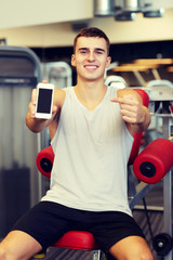 Fototapeta na wymiar smiling young man with smartphone in gym